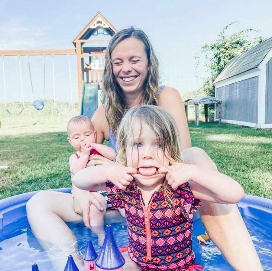 Mom shares candid photo with her two daughters while they play outside in a kiddie pool