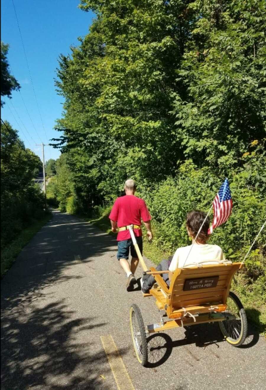 woman being walked by her husband in the chair he made for her