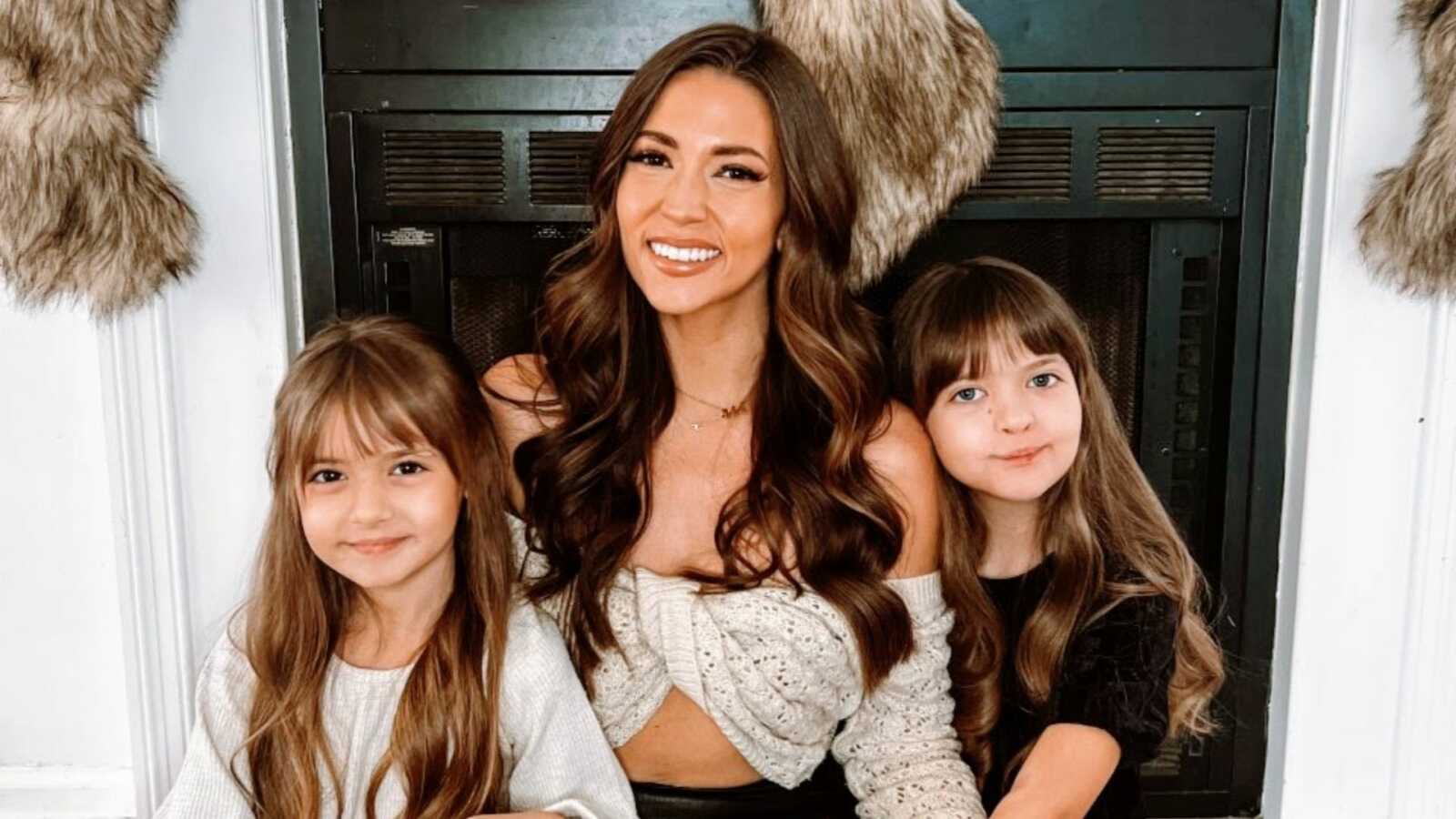 Single mom smiles for a photo with her two daughters