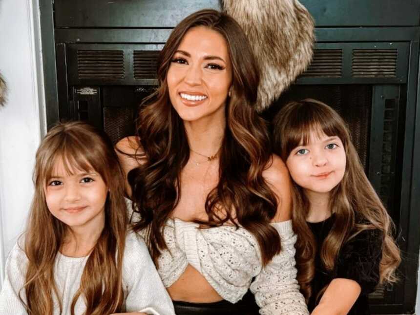 Single mom smiles for a photo with her two daughters
