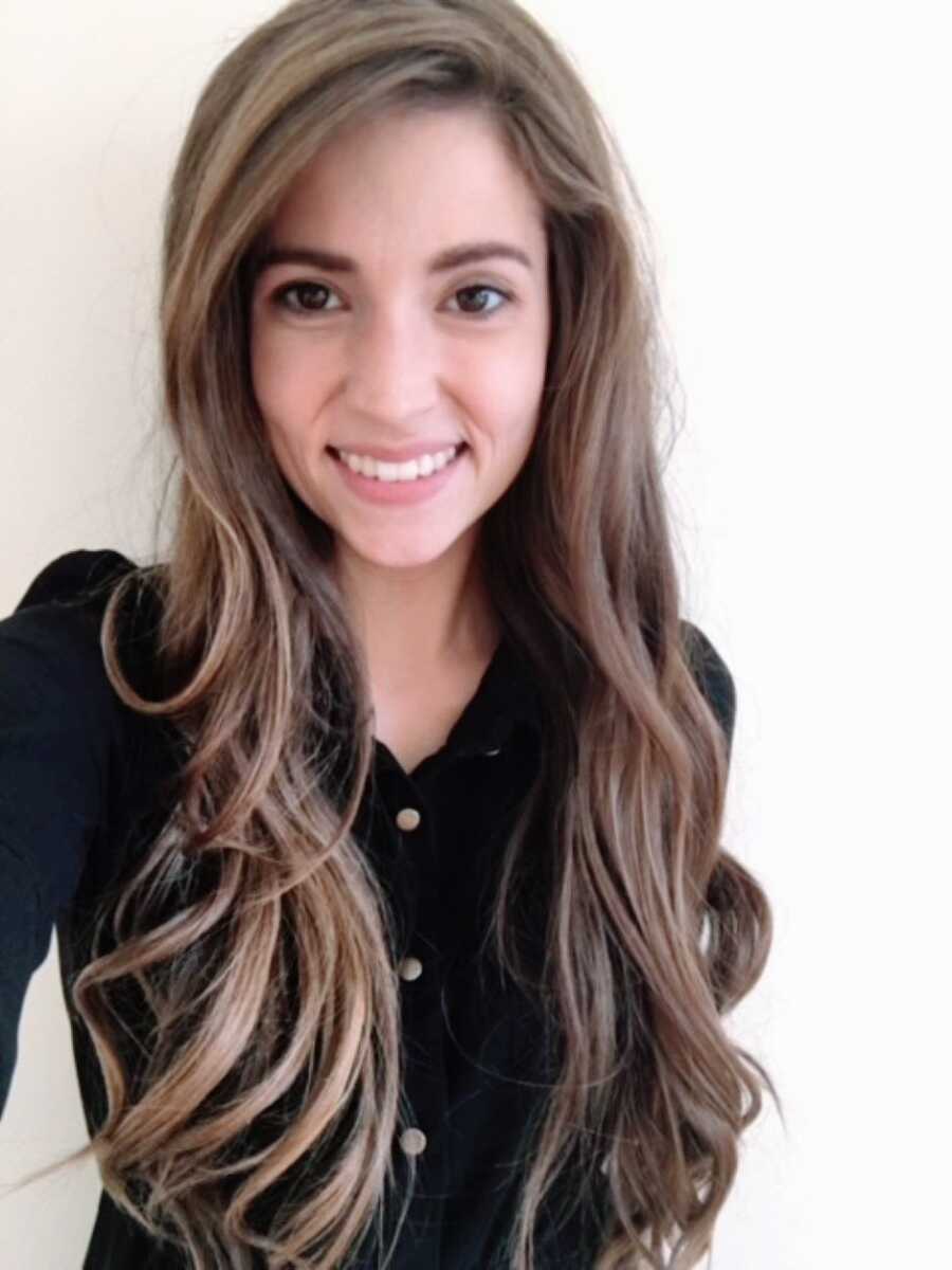 Woman in toxic marriage takes a selfie with her long brown hair curled while wearing a black button-down shirt