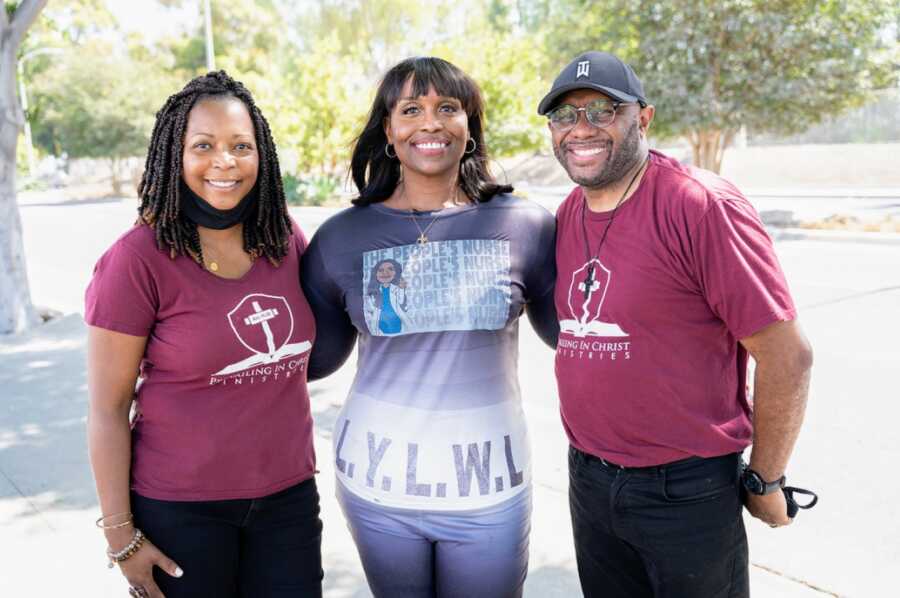 Two African American women and a man wearing Christ related shirts and one shirt that says THE PEOPLE'S NURSE