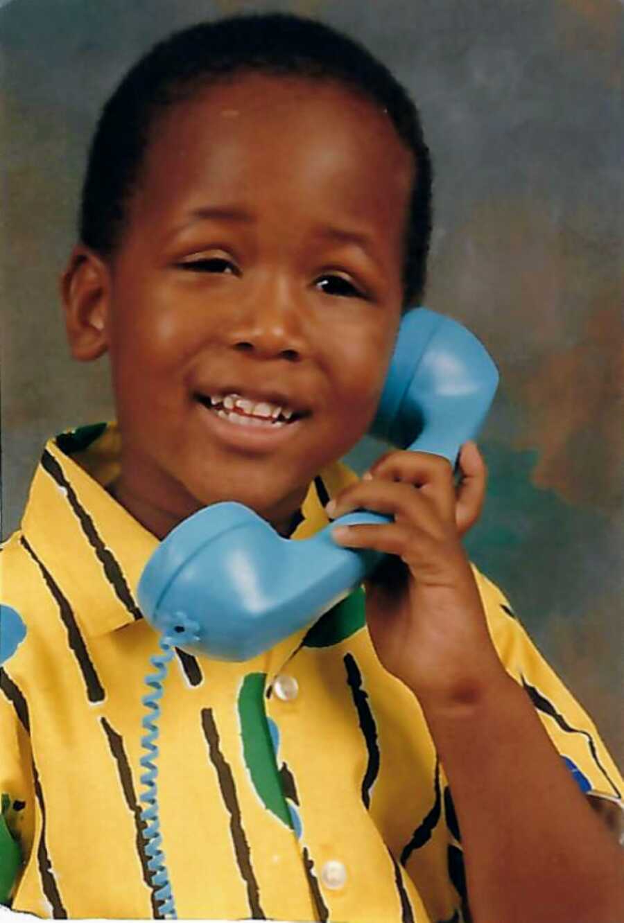 Young African American boy talking on a blue land line phone