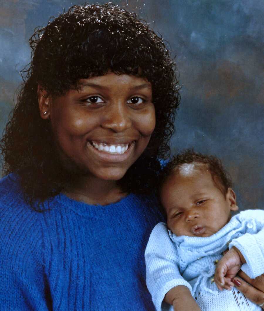 Mid shot of teen African American mom holding her newborn baby and smiling