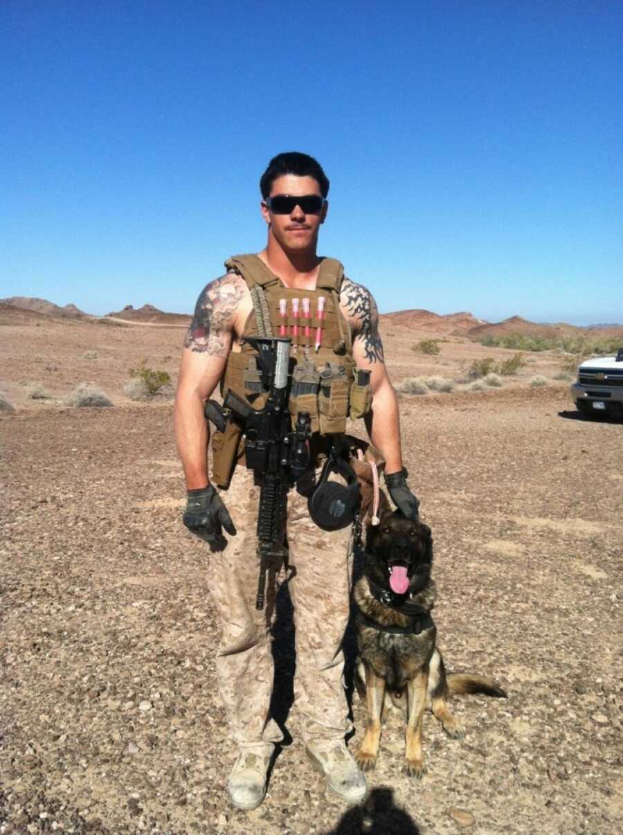 Marine looks serious while taking a photo out in the field with his K-9 partner at his side
