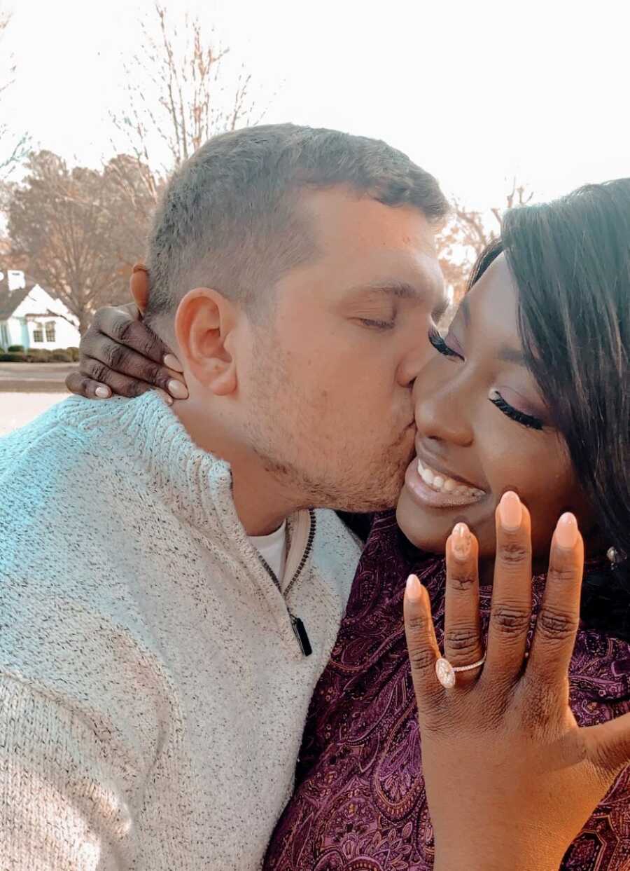 Man kisses his fiancé on the cheek while she shows off her engagement ring after he just proposed 