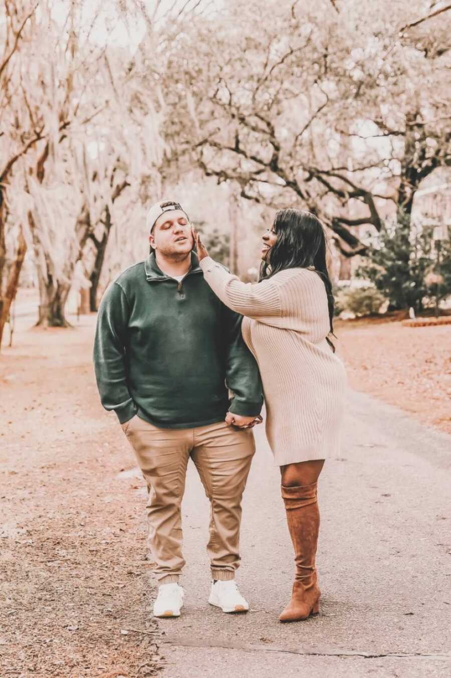 Couple take candid photo of her wiping his face while taking engagement photos