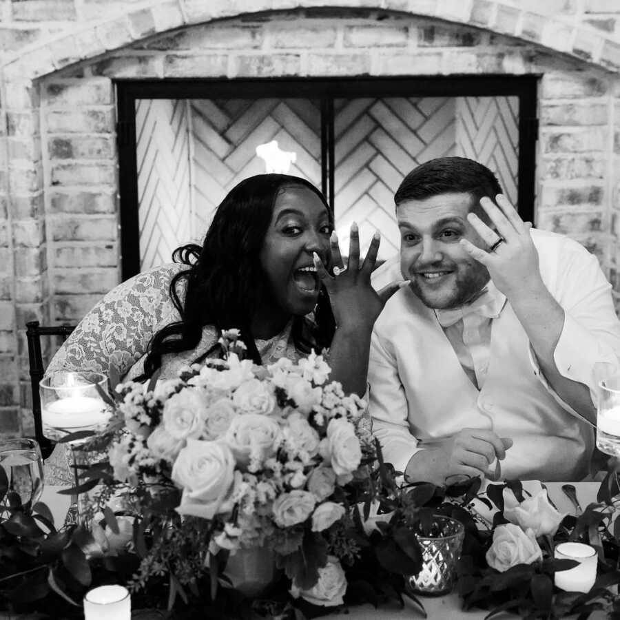Newlyweds look happy as they show off their wedding rings while at their wedding reception