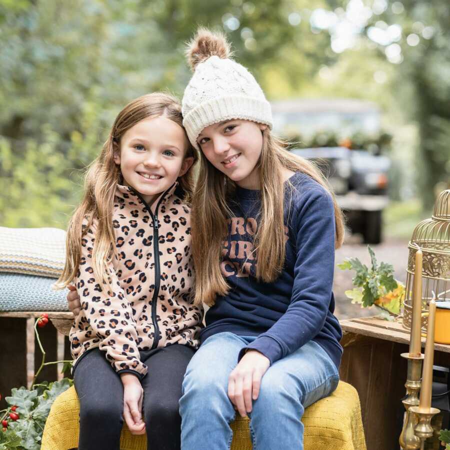 sisters taking a photo in the woods