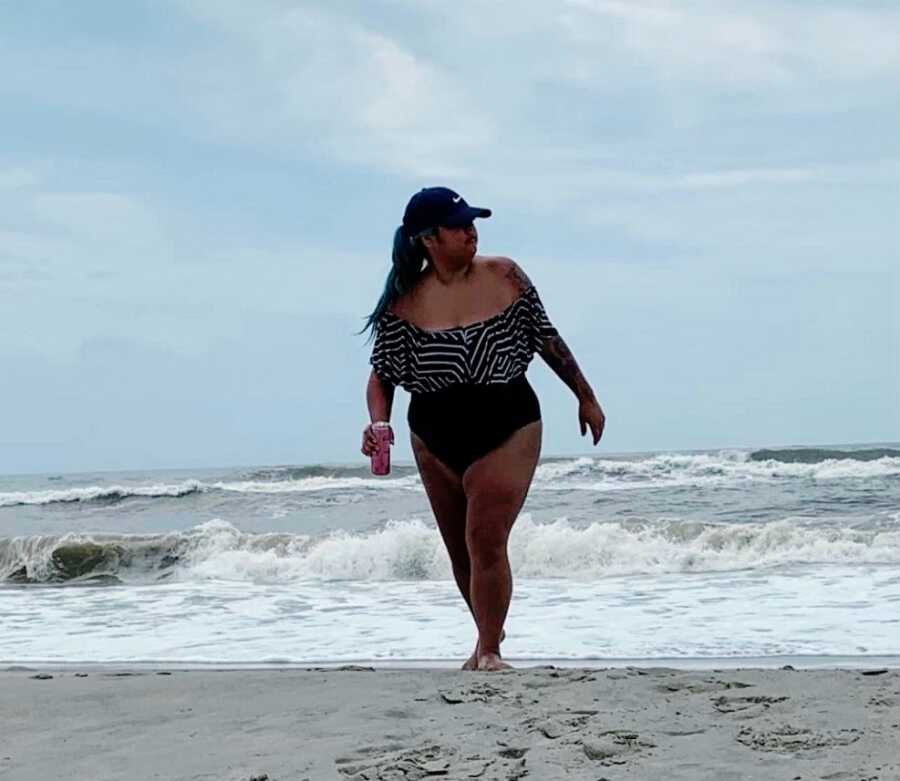 A woman wearing a bathing suit stands at the beach
