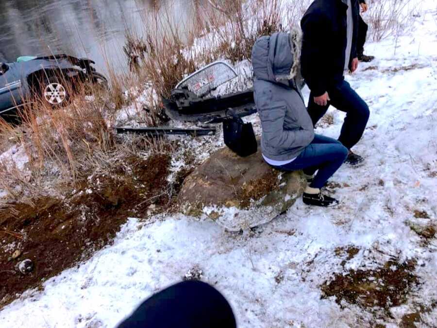 pregnant woman sits on rock after being saved from her car that crashed into a river