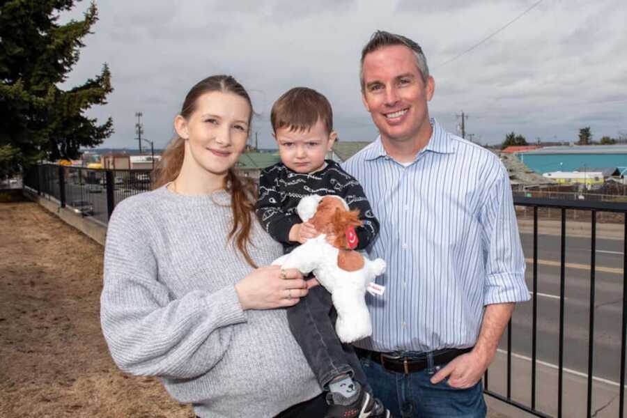 woman holds her son who she was pregnant with at the time of the crash, and stands with the man who saved her