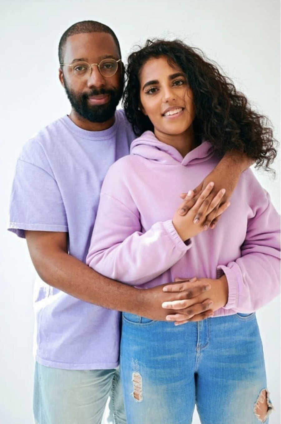 Pakistani wife and Black husband stand with their arms around one another in embrace