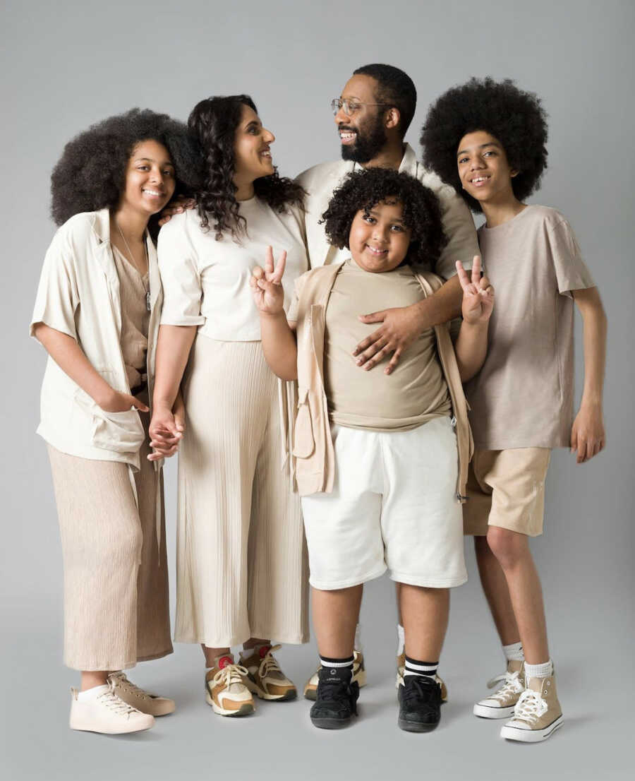 Mixed race family stand together, all are smiling and laughing with one another