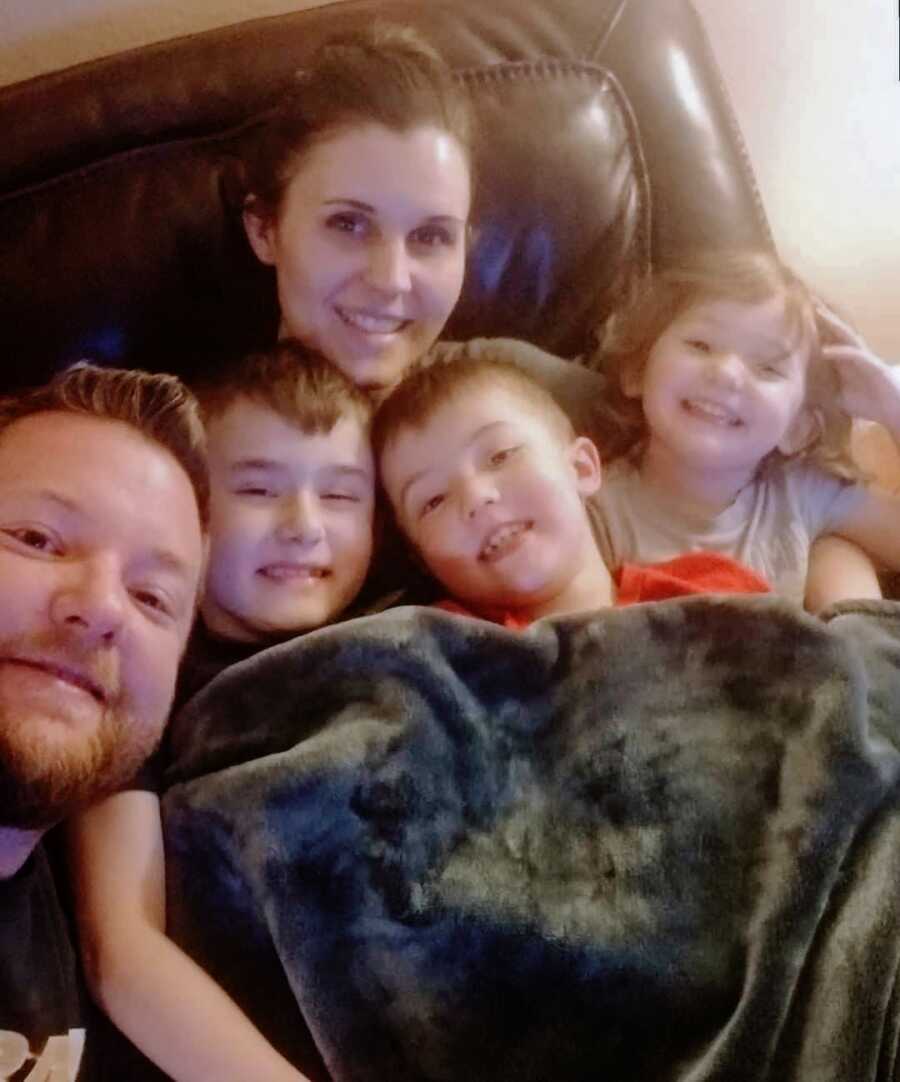 Duchenne parents cuddle on the couch with their two sons with Duchenne and their daughter