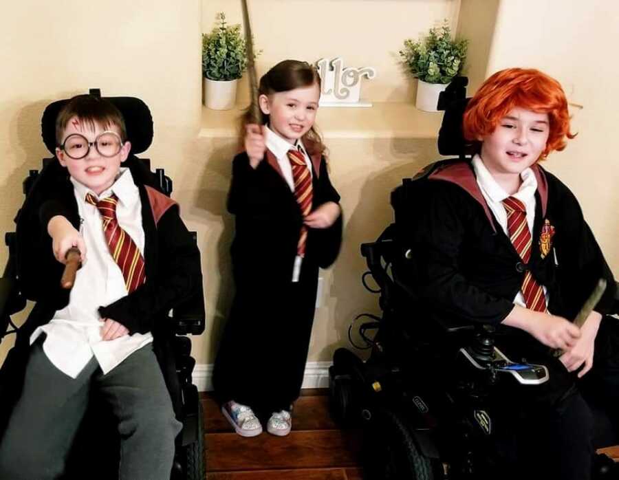 two boys with Duchenne sit in their wheel chairs dressed in Harry Potter costumes, with their little sister also dressed up