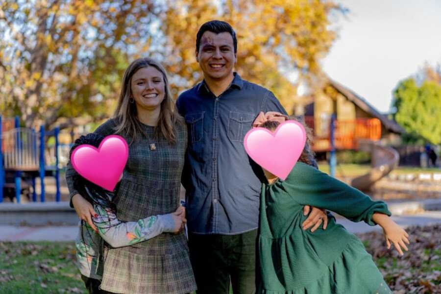 Young foster parents take family picture with two foster sisters.