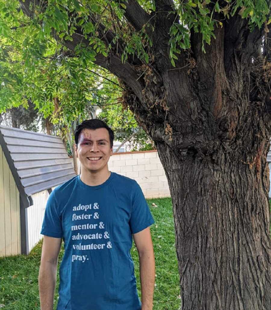 Man wears blue shirt that says, "Adopt & foster & mentor & advocate & pray."