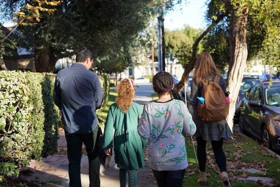 Foster family walks together holding hands.