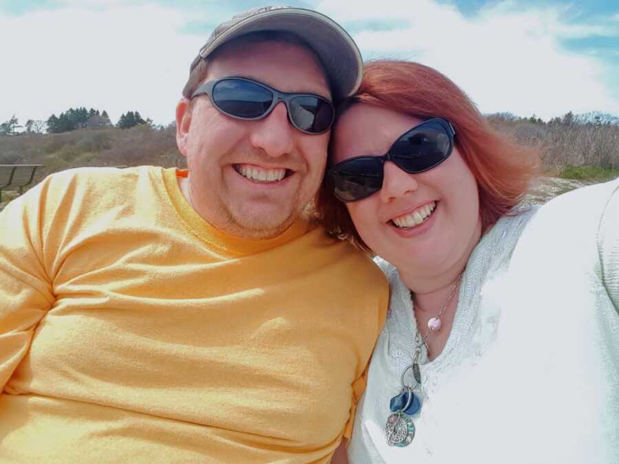 husband and wife smile widely while posing for a selfie