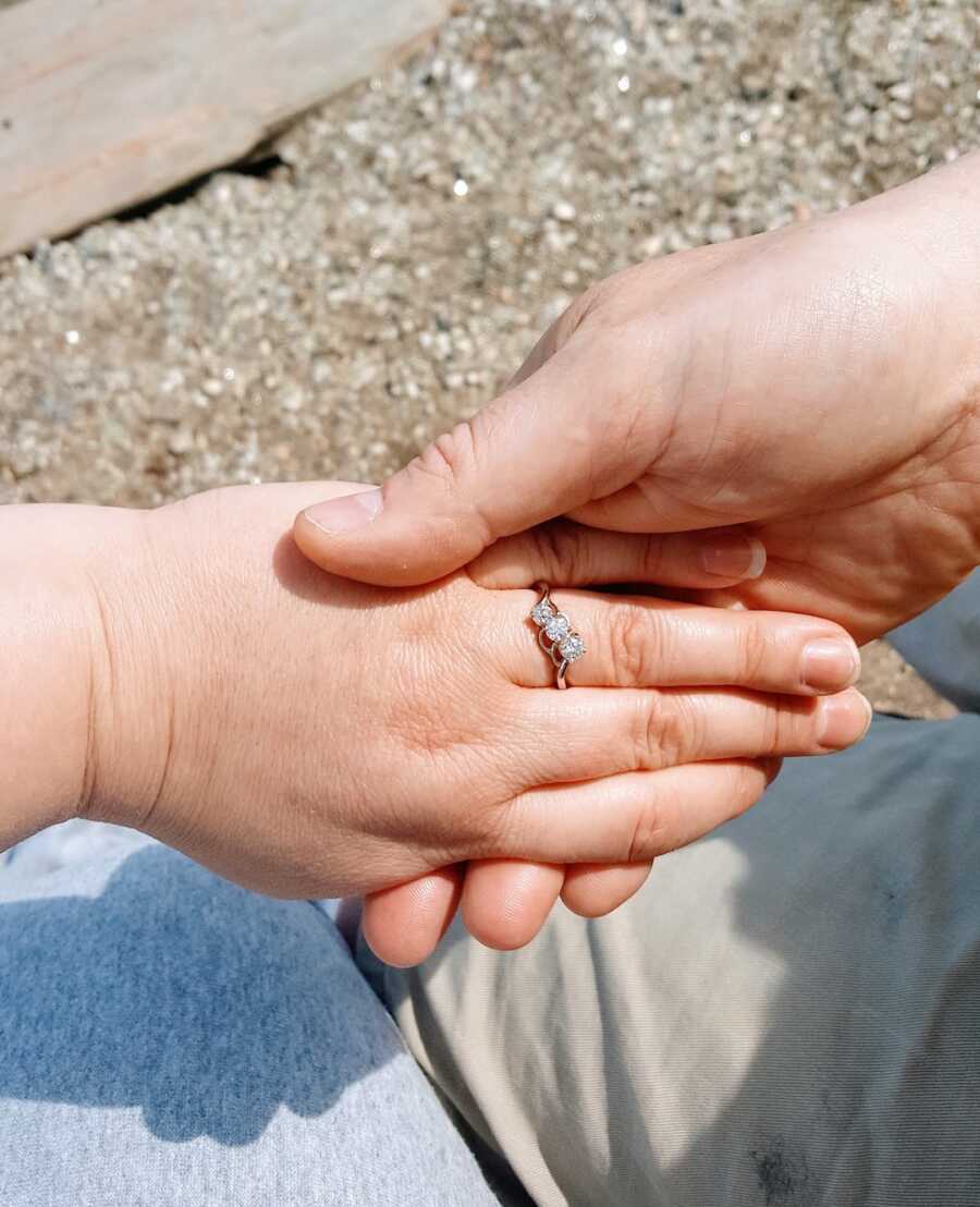 man holds his fiancé's hand while she is wearing her engagement ring