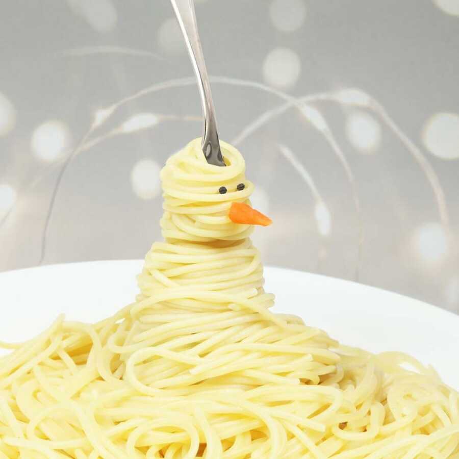 pasta twirled onto a fork to look like a snowman with a small carrot nose