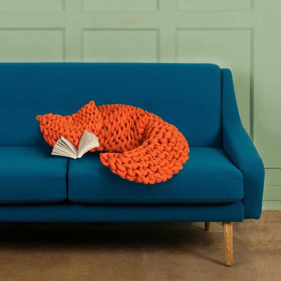 blankets positioned on a couch with book to look like a fox curled up on the couch