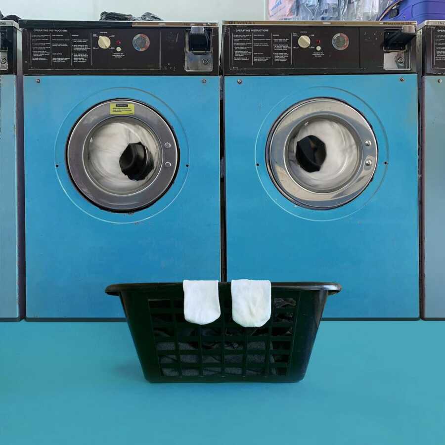 washing machines and laundry basket positioned and photographed to look like a silly face