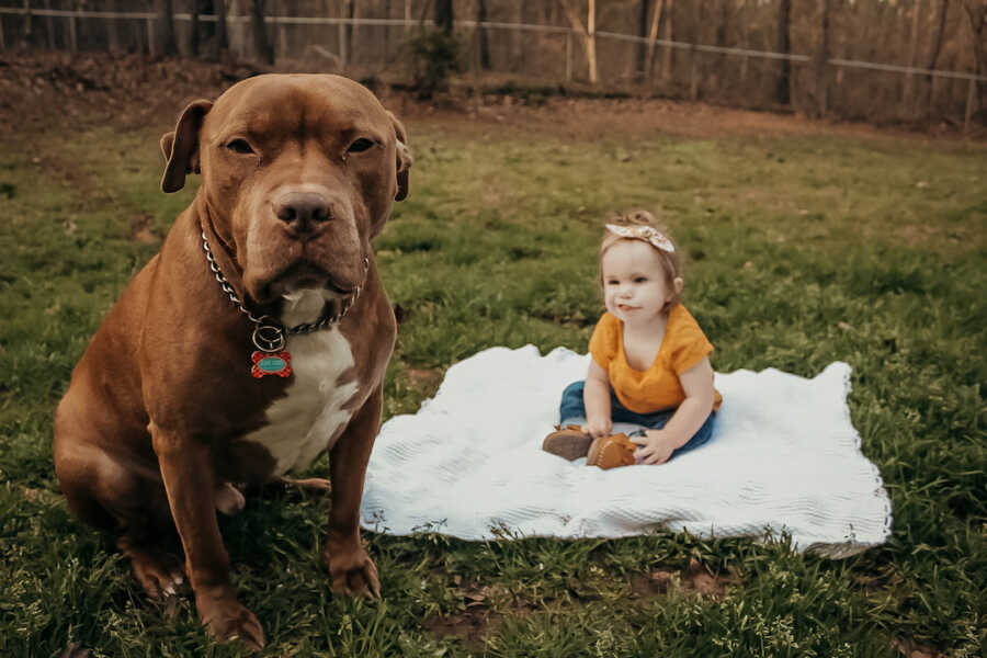 young girl sits with her protective dog