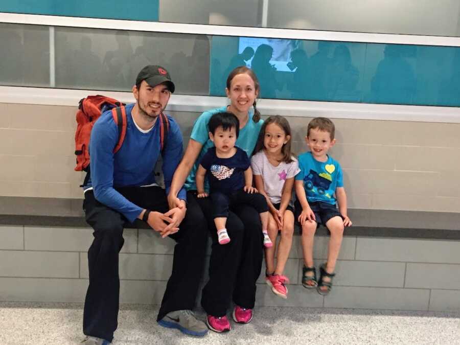 adoptive parents sit with their two biological children and one adopted child