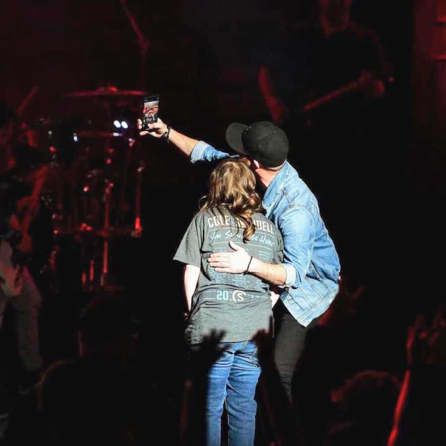 Cole Swindell takes a selfie with the girl he invited on stage at his concert