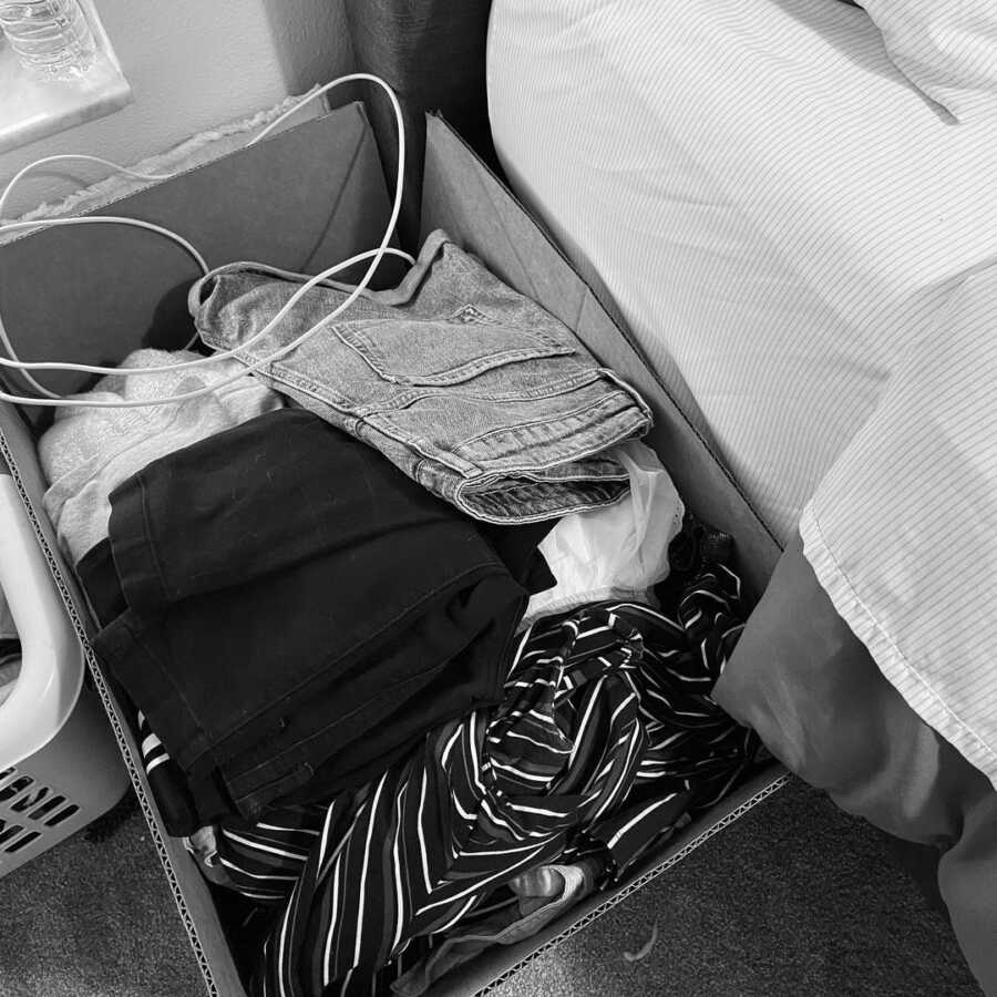 box of clothes from a loved one who has passed sits next to a bed