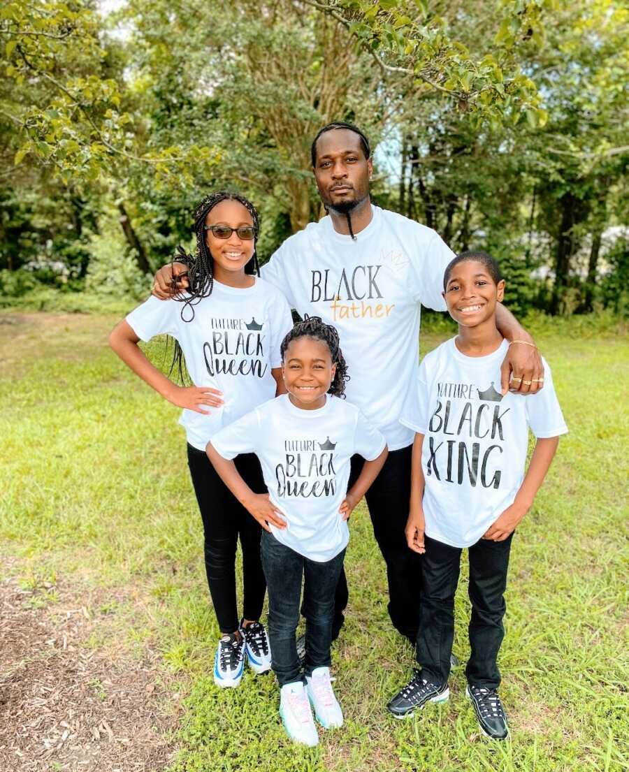 step-father stands with his three children, all are wearing black empowerment shirts