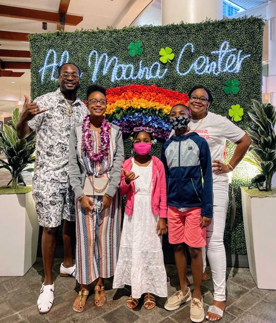 blended family stands in front of a photo wall, parents and their three children