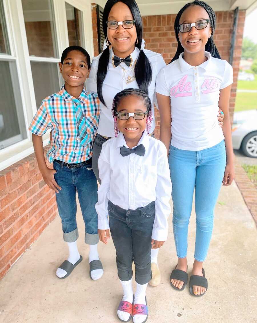 mother stands with her three children, two daughters and a son