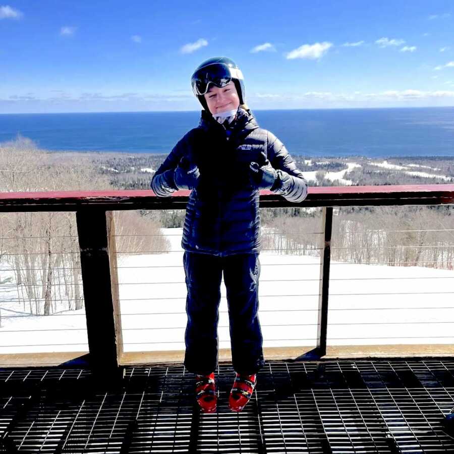 16 year old girl poses with two thumbs up in a ski outfit
