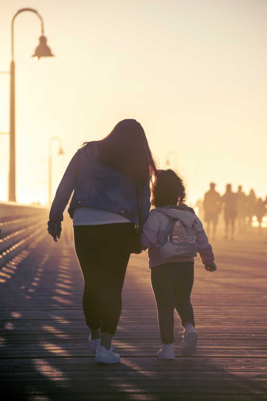 mom and daughter walking on the pier