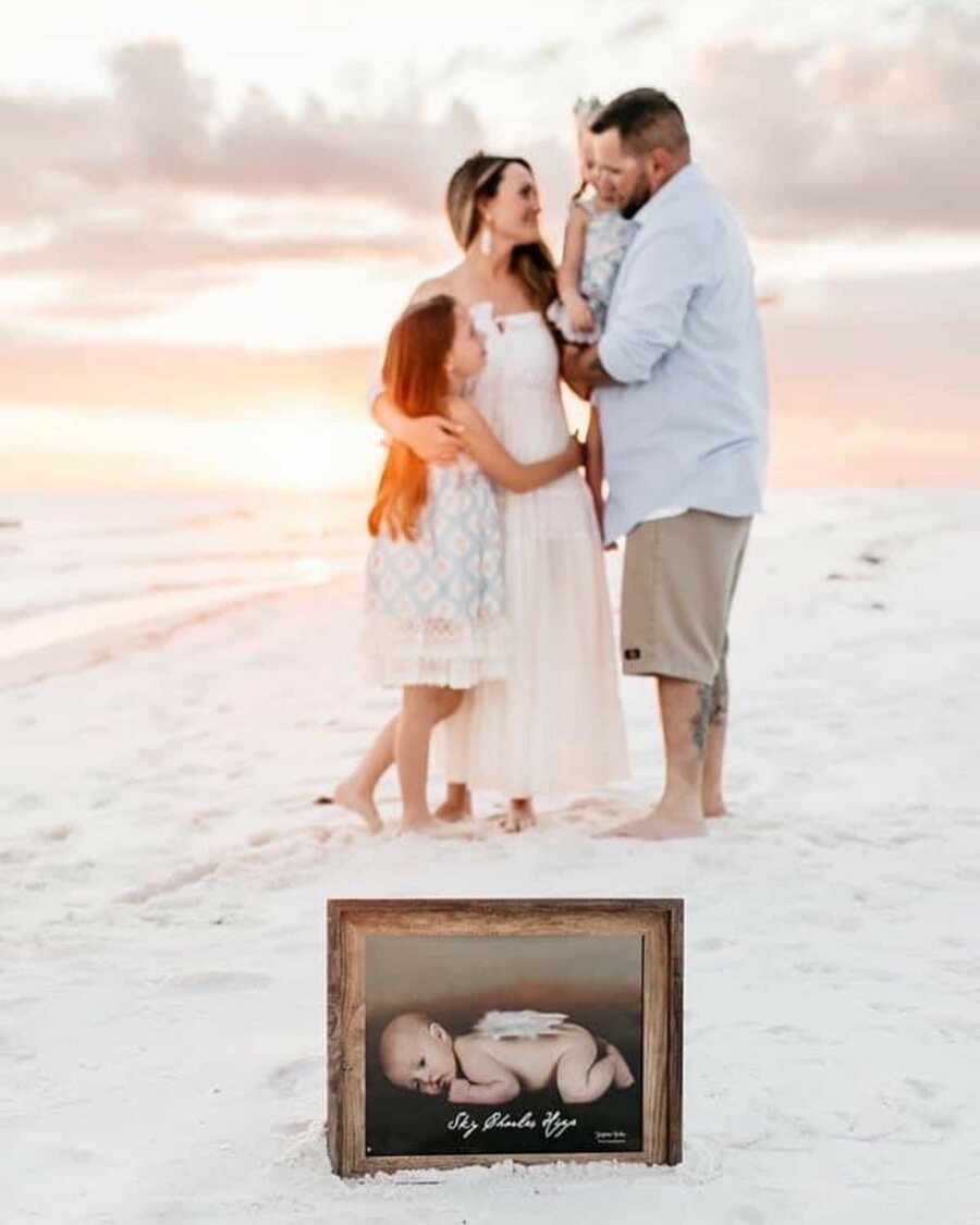 family stands together while an image of their son/brother who passed away from S.I.D.S. sits in front of them