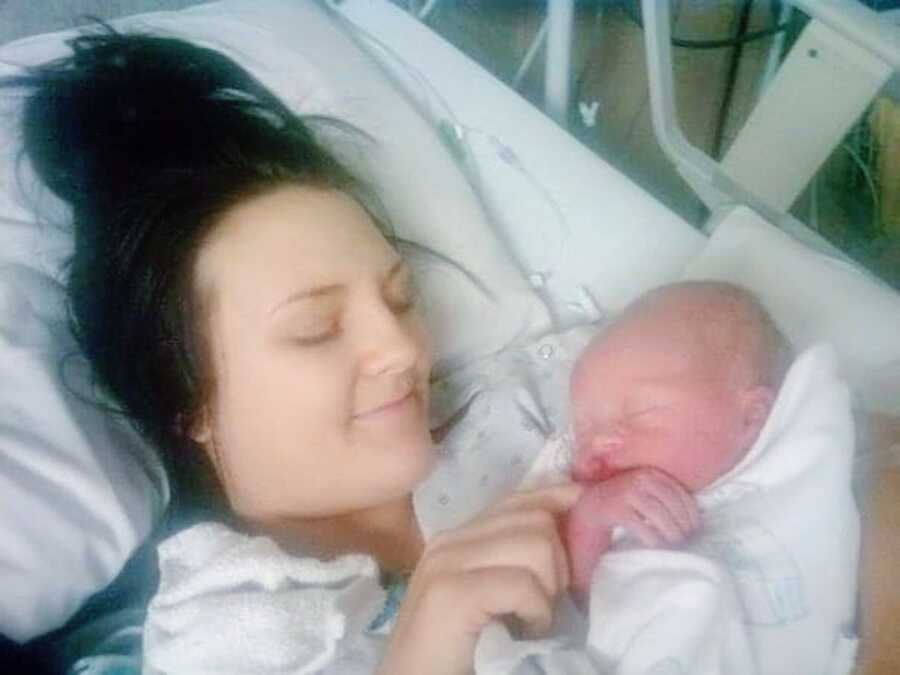 mother holds her newborn son to her chest in a hospital bed