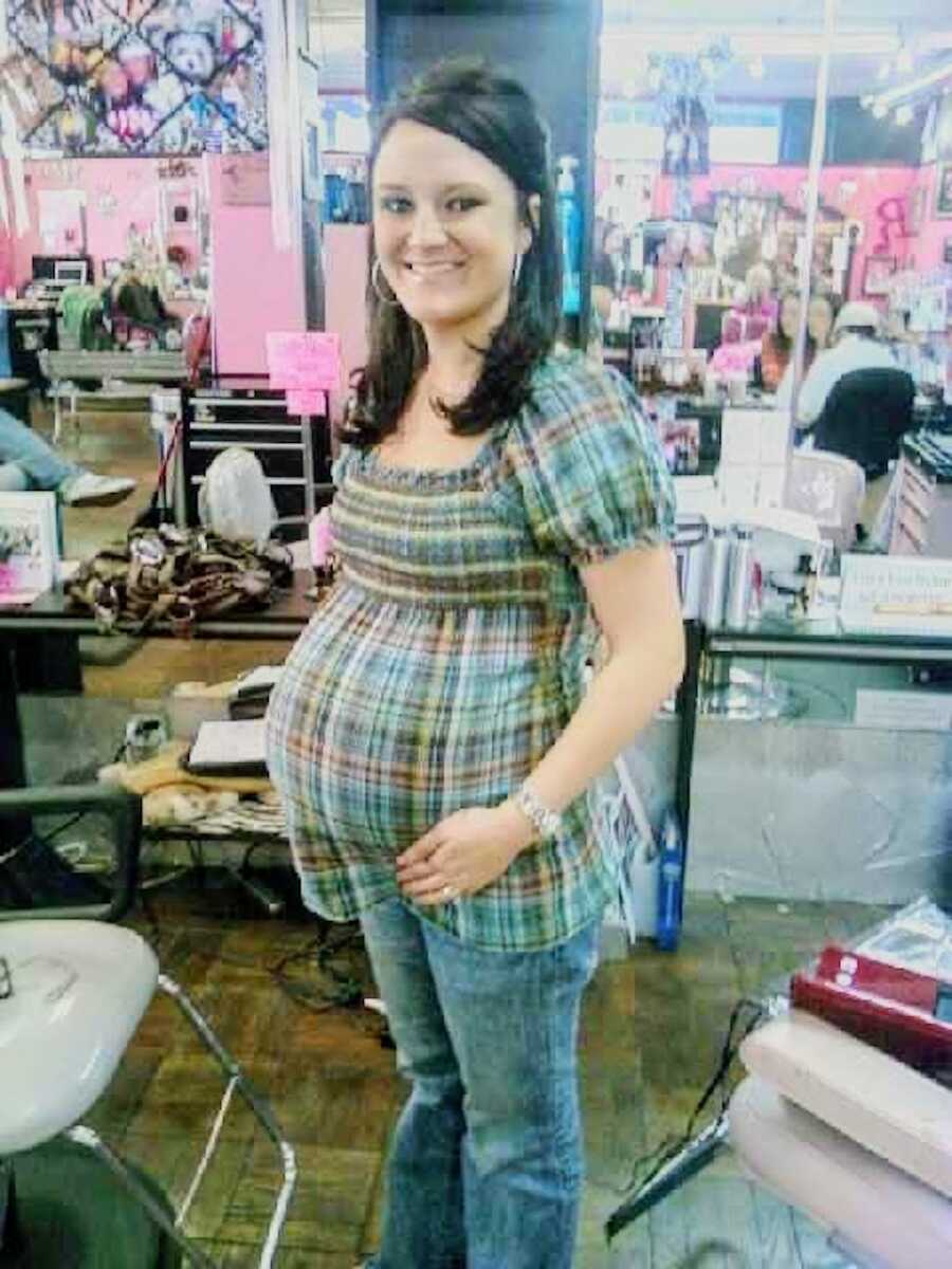 young pregnant mom shows off her belly bump, smiling widely