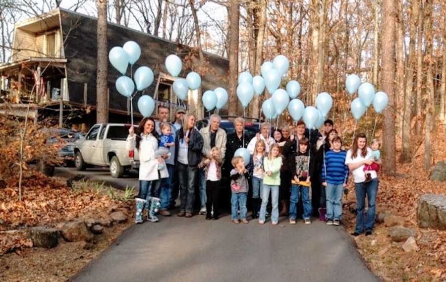 family gathering to remember losing baby to S.I.D.S., all are holding blue balloons