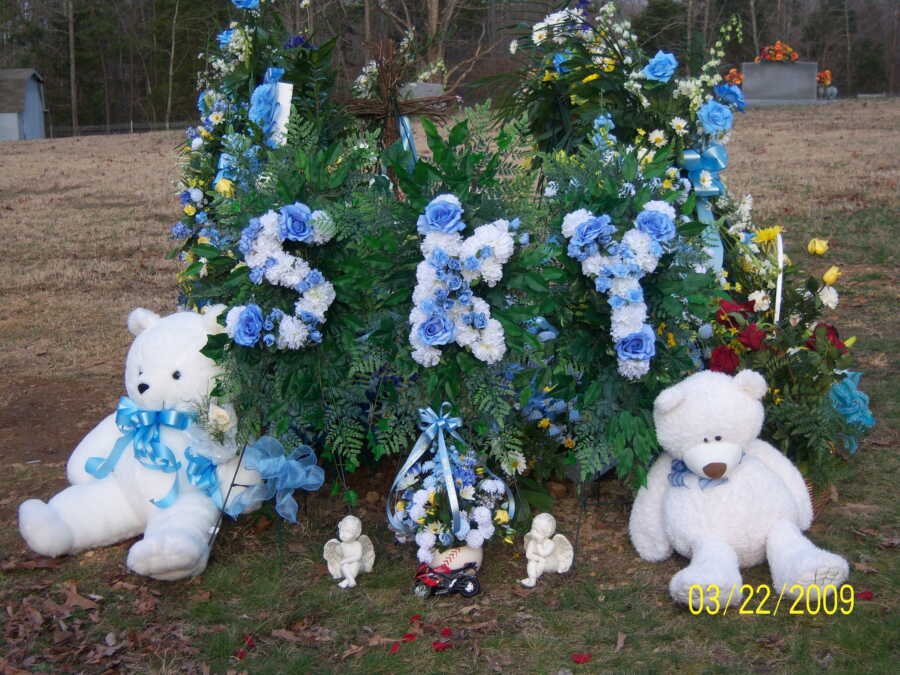 memorial flower arrangement that says "sky" in blue and white flowers with teddy bears