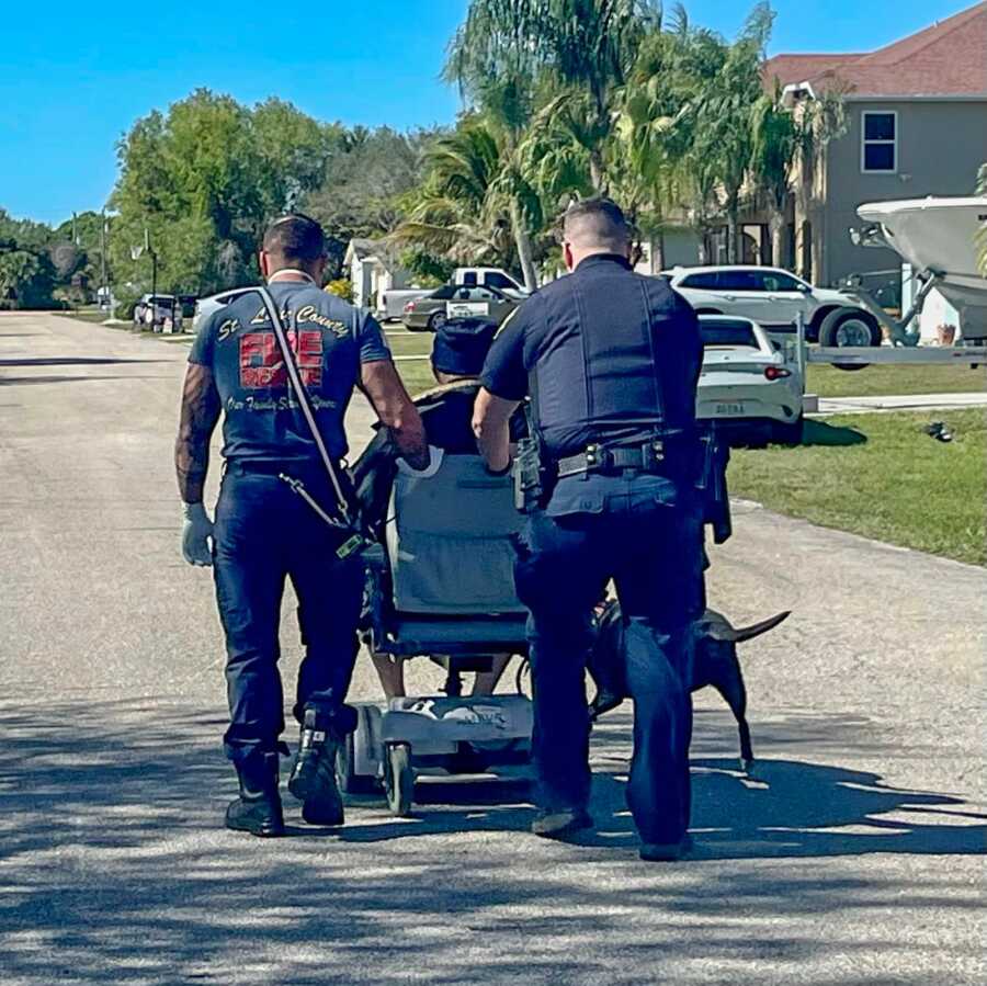 First responders push elderly man home in damaged electric wheelchair.