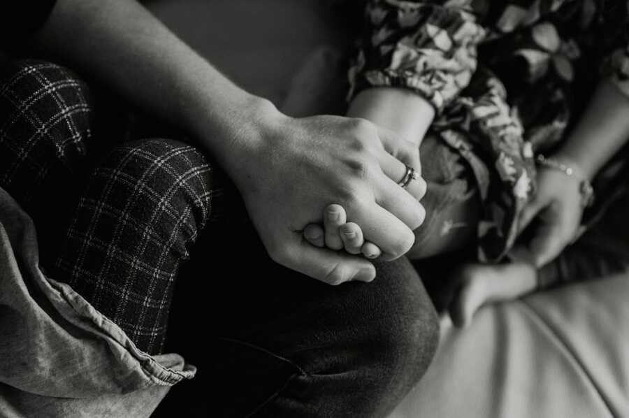 mother holds her child's hand in her lap