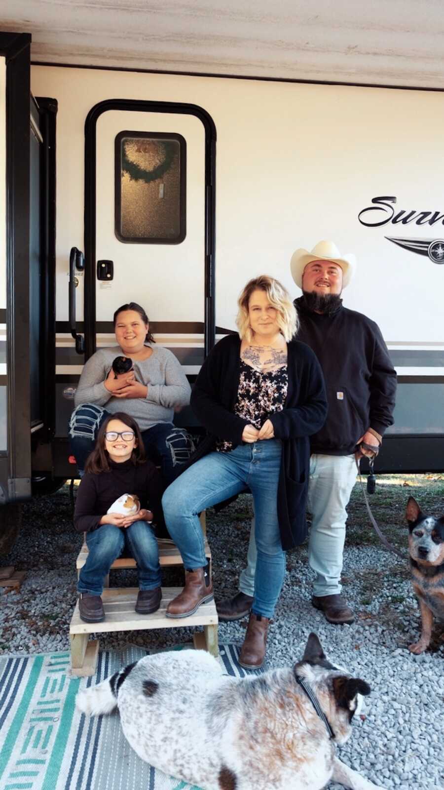 family stands outside of an RV with their dogs, family is two daughters and parents