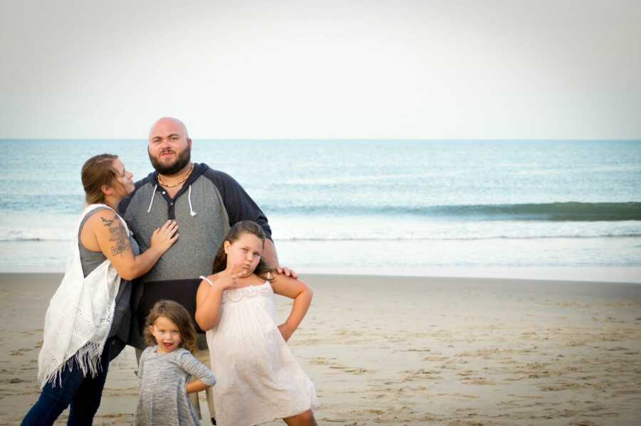 family takes a photo together on the beach, two daughters with husband and wife