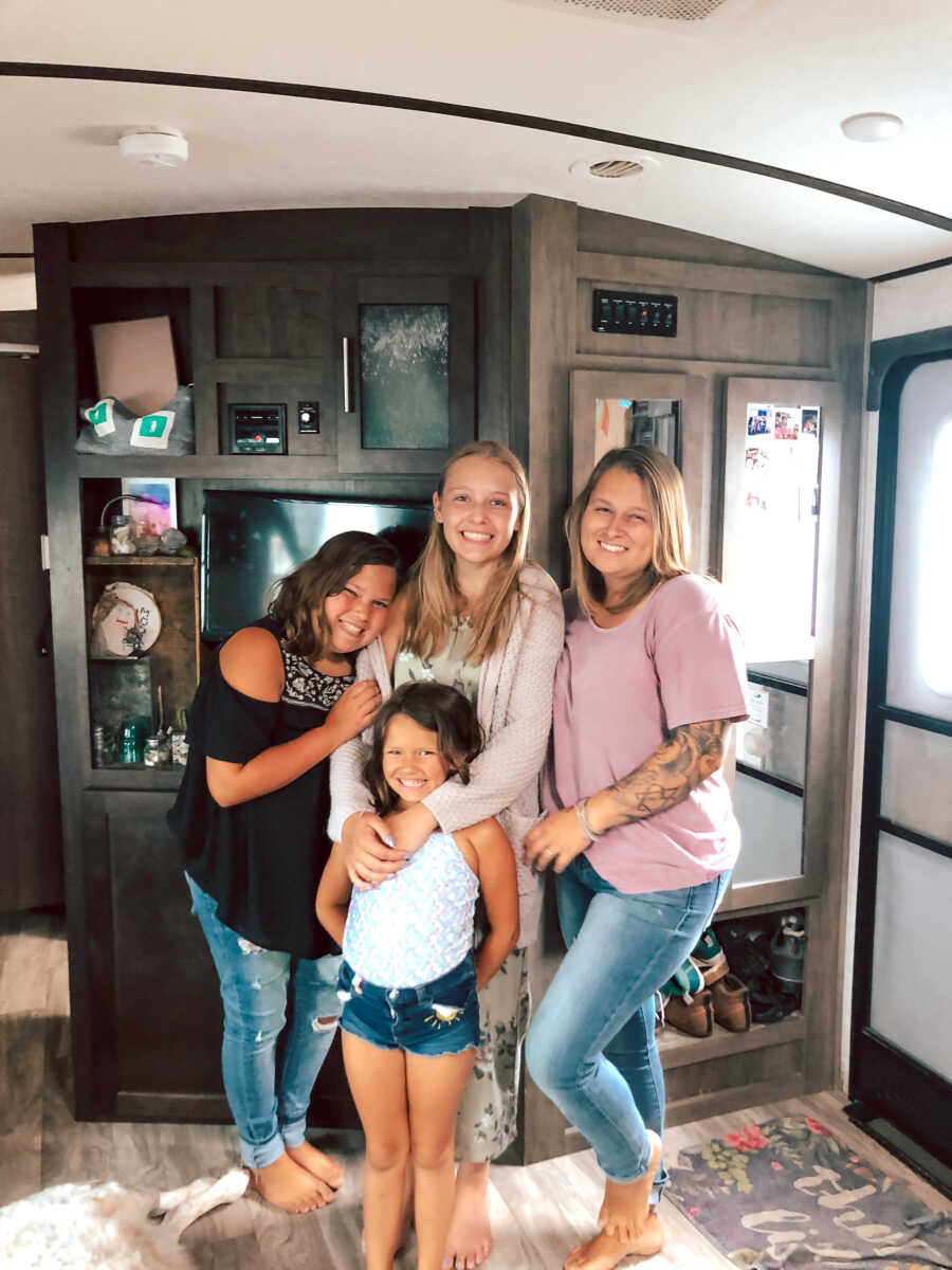 Mother stands with her three daughters, two live with her one lives with her family through open adoption