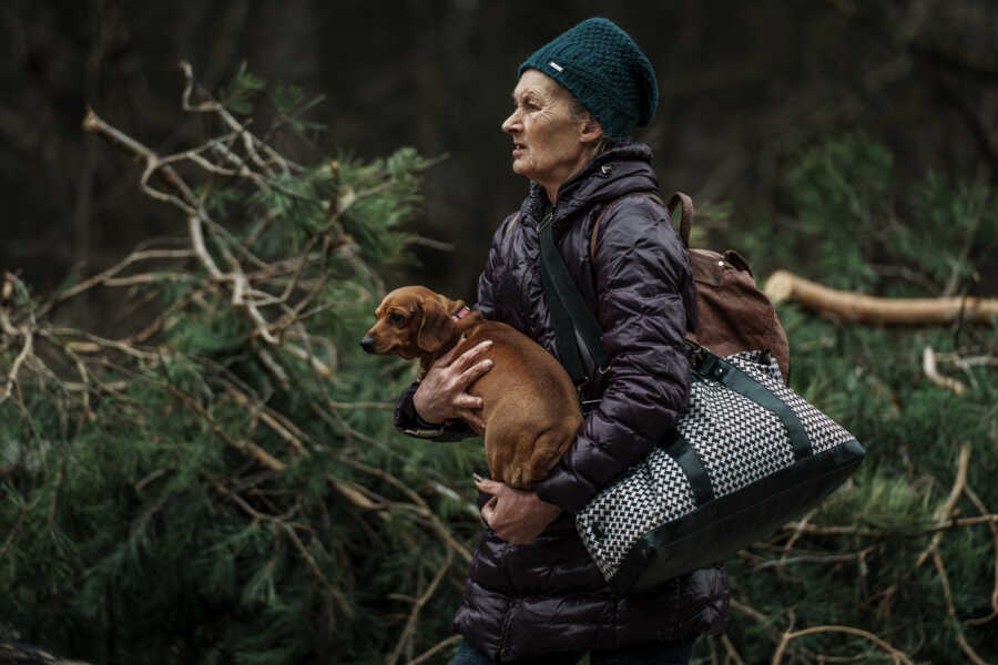 Ukrainian woman carries dog as she evacuates.