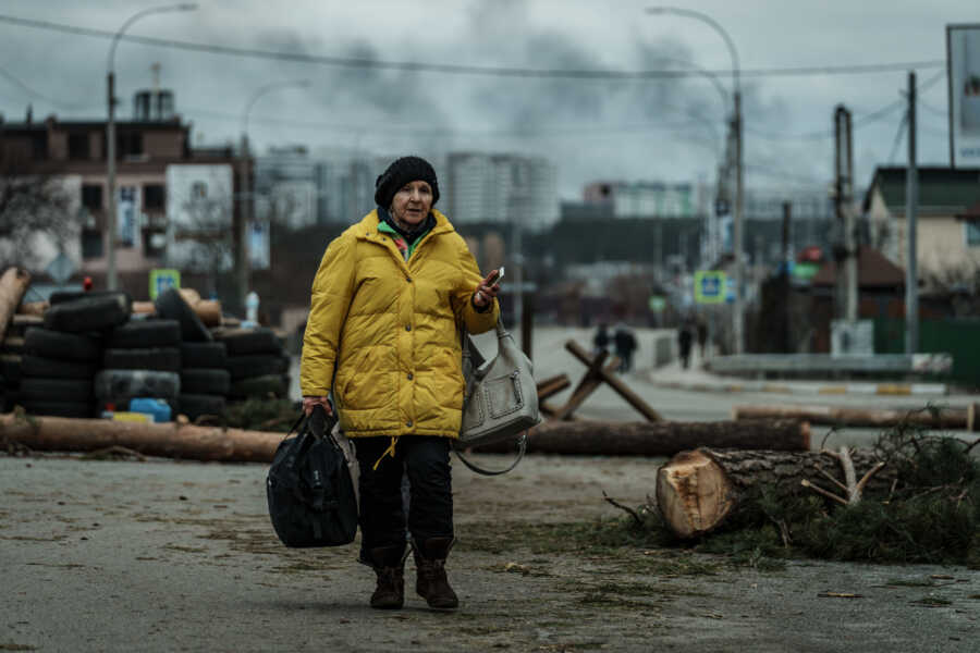 Ukrainian woman walks through the street carrying travel bag.