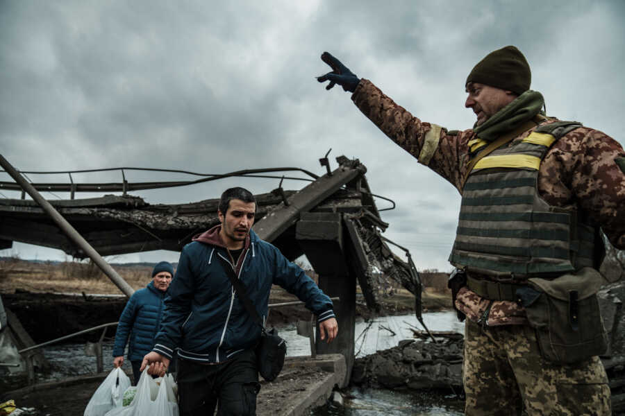 Ukrainian military member directs people fleeing.